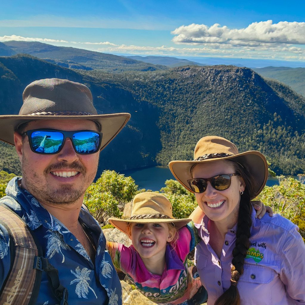 Happy family after achieving a milestone National Park hike while travelling Tasmania, Australia wearing hats and standing in sunshine and blue skies.