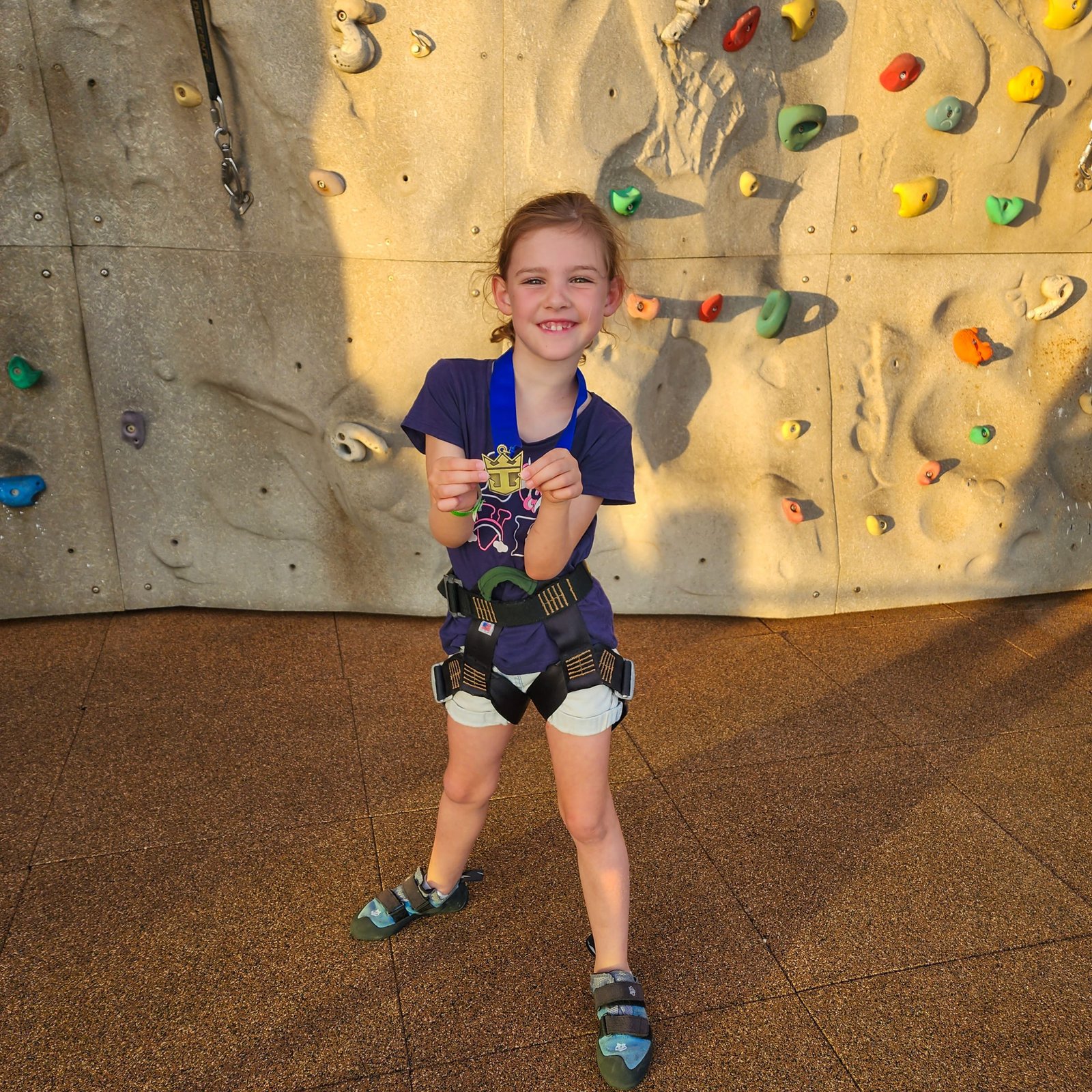 Young girl proudly showing her medal at the rock climbing wall