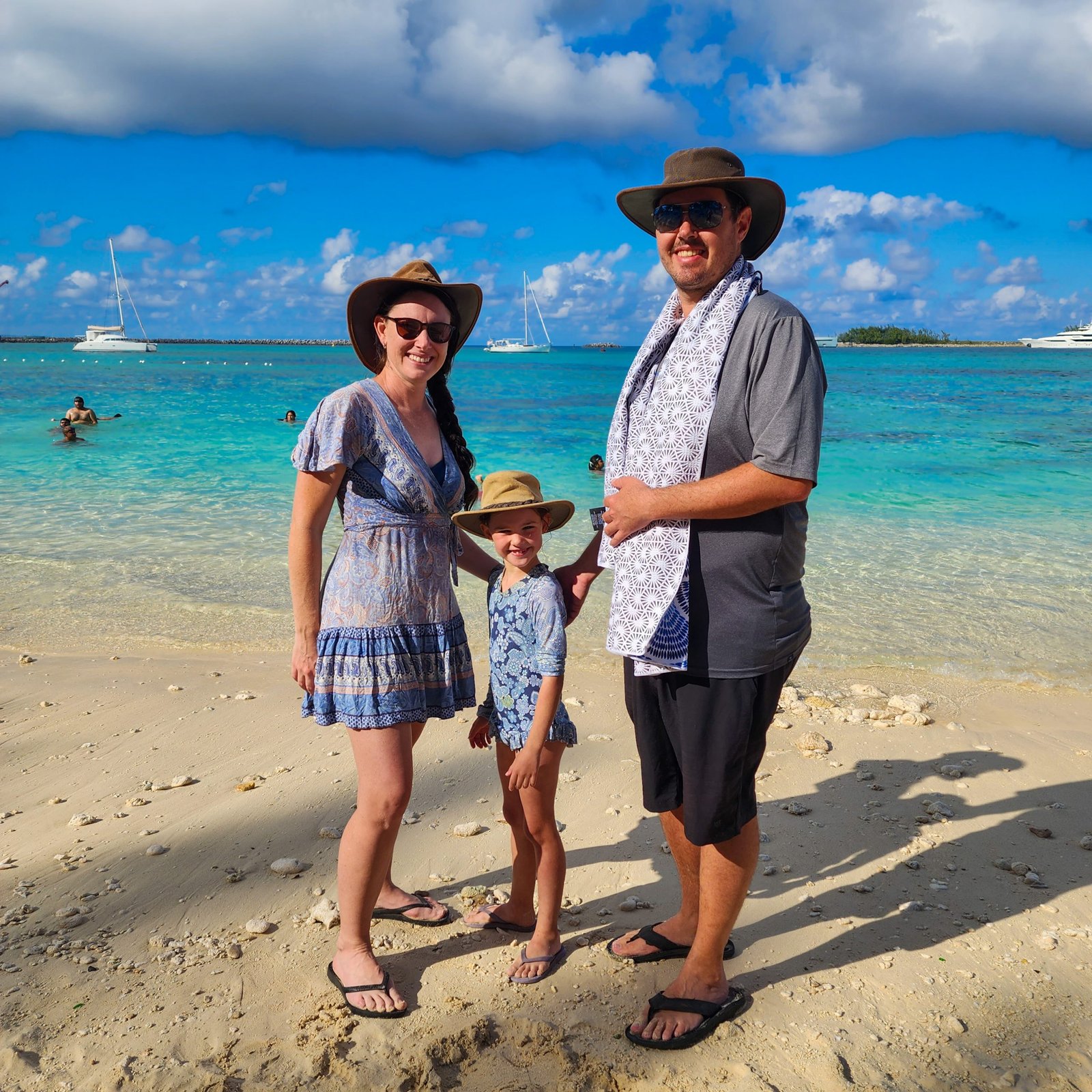 Family standing at the beach in the Bahamas with the sun shining and blue water.