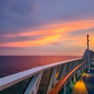 Yellow and orange sunset clouds over the edge of a cruise ship